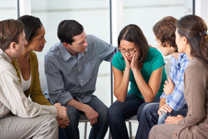 a woman being comforted in group therapy by her peers during a group counseling session
