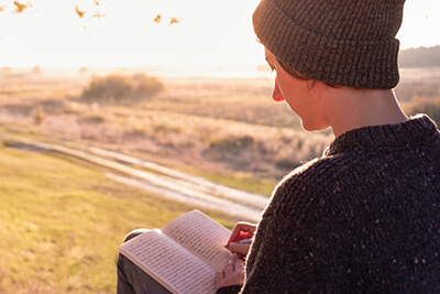 person writing in journal looking out at beautiful landscape