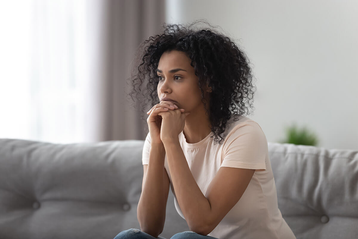 woman sitting on couch experiencing post-acute withdrawal syndrome