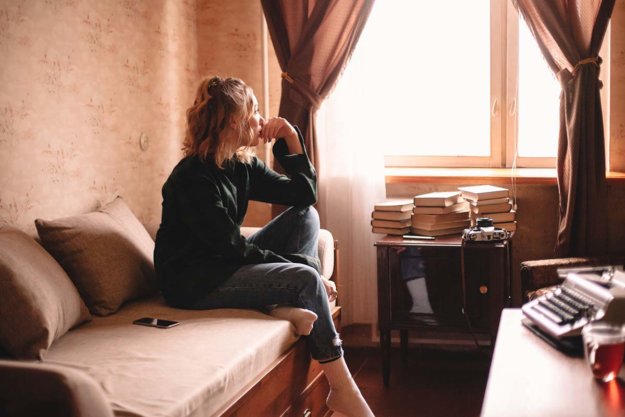 common relapse triggers woman sitting on couch pondering Common Relapse Triggers