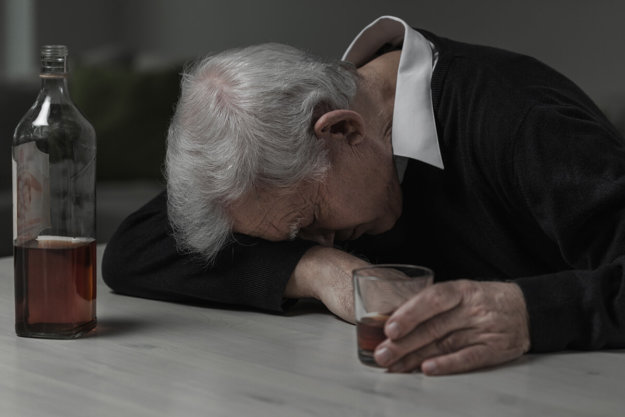 man leaning on a table with a drink experiencing the Risks of Alcohol Abuse