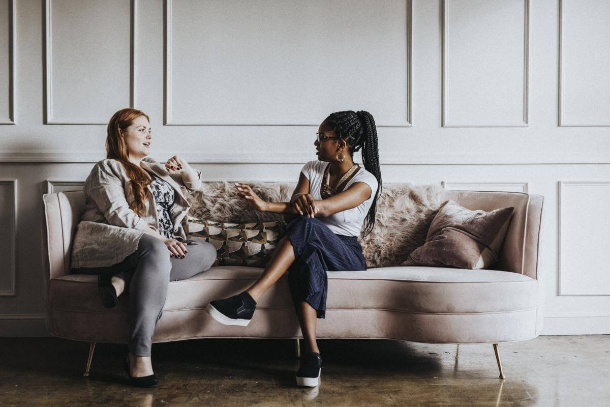 two women in conversation on a couch during residential rehab