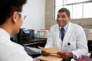 smiling doctor behind desk discussing cocaine addiction treatment with a patient