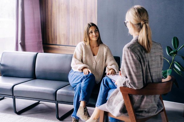 Benefits of Long-Term Rehab woman in sunlit room discussing the benefits of long-term rehab with her counselor