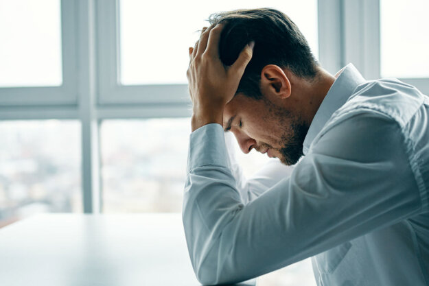 Man in an office setting with his head in his hands contemplating the long-term effects of cocaine