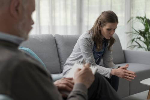 Woman in benzo rehab program sits on couch as therapists listens.