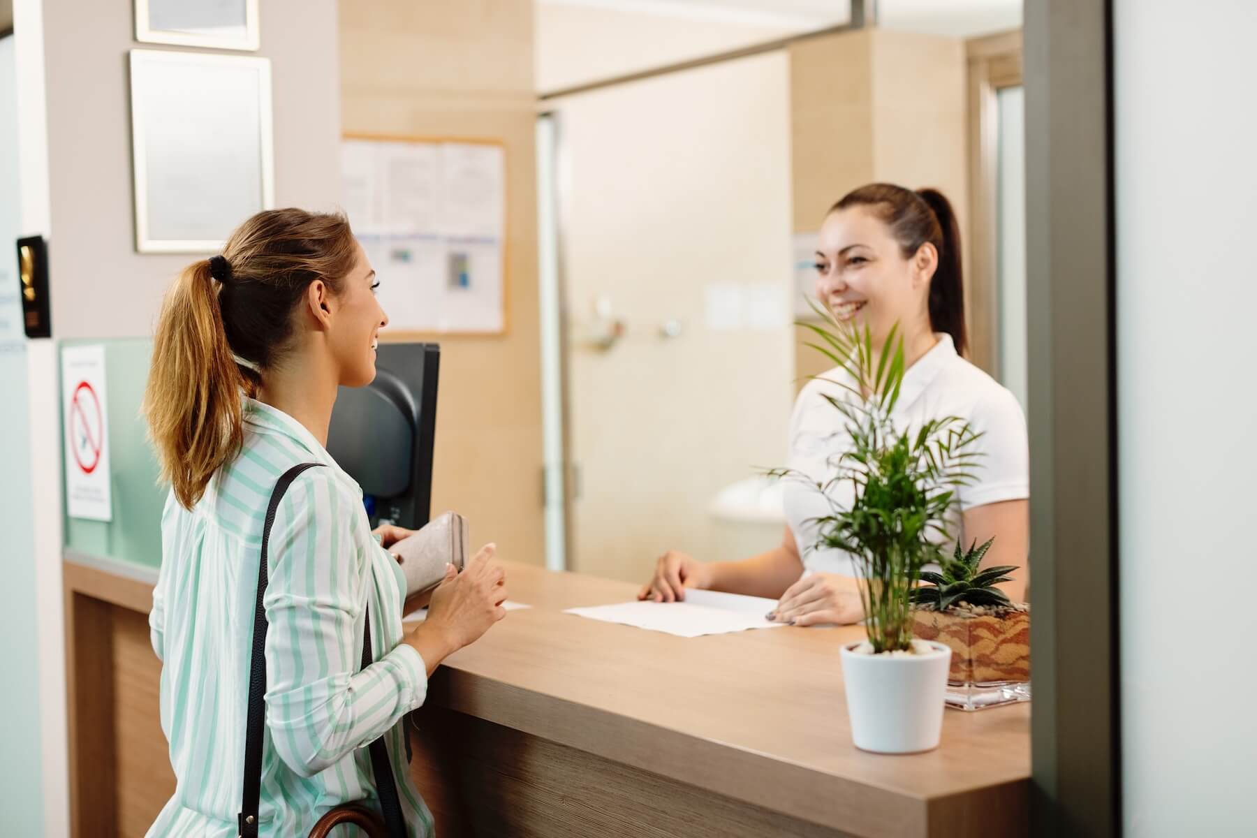 Happy woman talking to a receptionist while arriving at the spa. woman talks with receptionist about california rehab centers that accept insurance