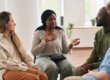 Diverse group of people in a therapy circle sharing experiences during an addiction recovery meeting