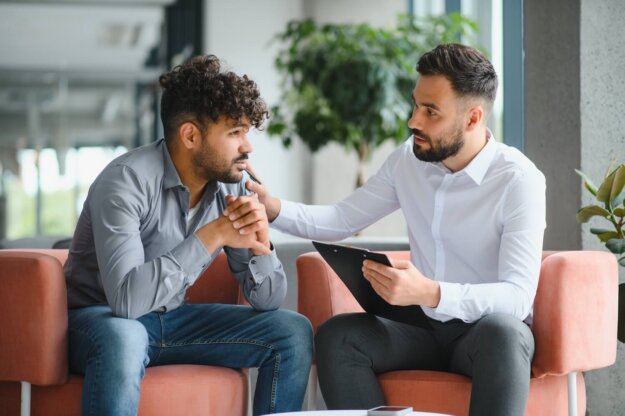 Male therapist comforting and talking with a client during an addiction recovery counseling session