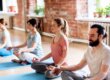 Group of people meditating on yoga mats in a bright studio as part of holistic rehab therapy