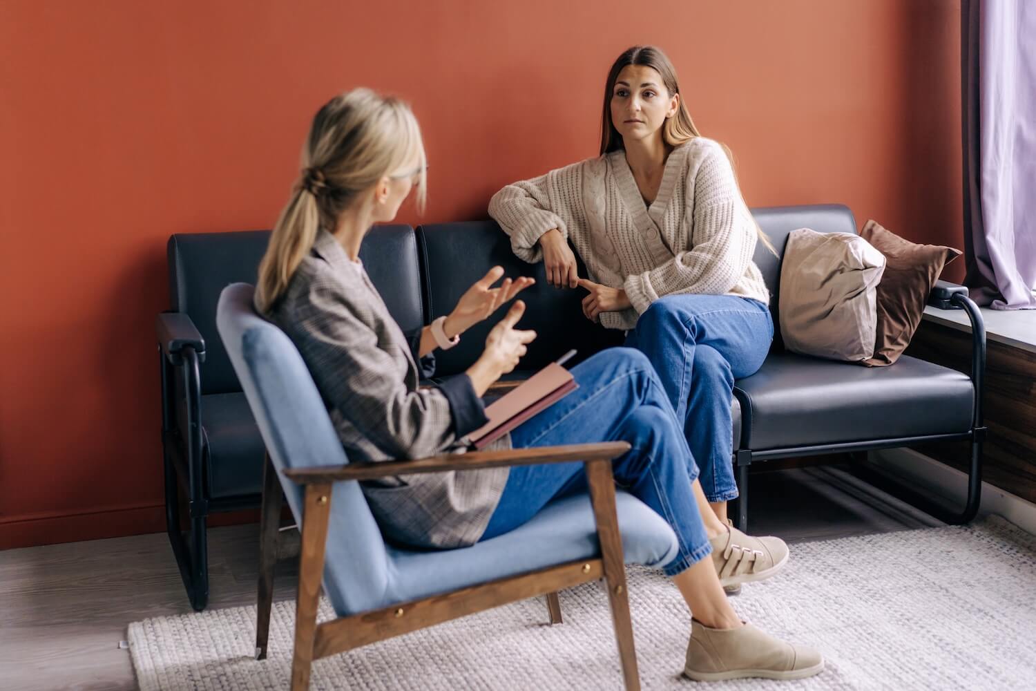 How Long Does Rehab Last Understanding Treatment Timelines Two women sitting in a counseling session discussing mental health and recovery in a calm office