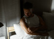 Man in bed scratching meth sores on his arm