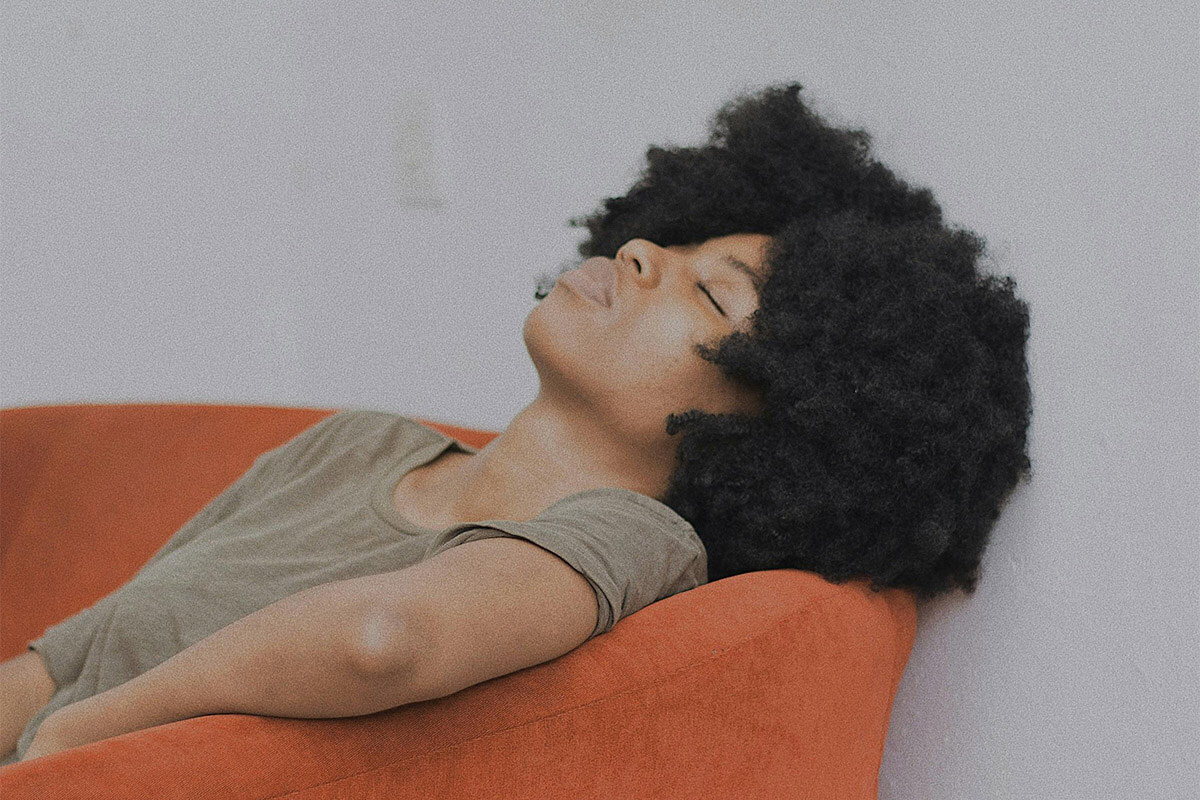 Black woman resting in orange chair during detox